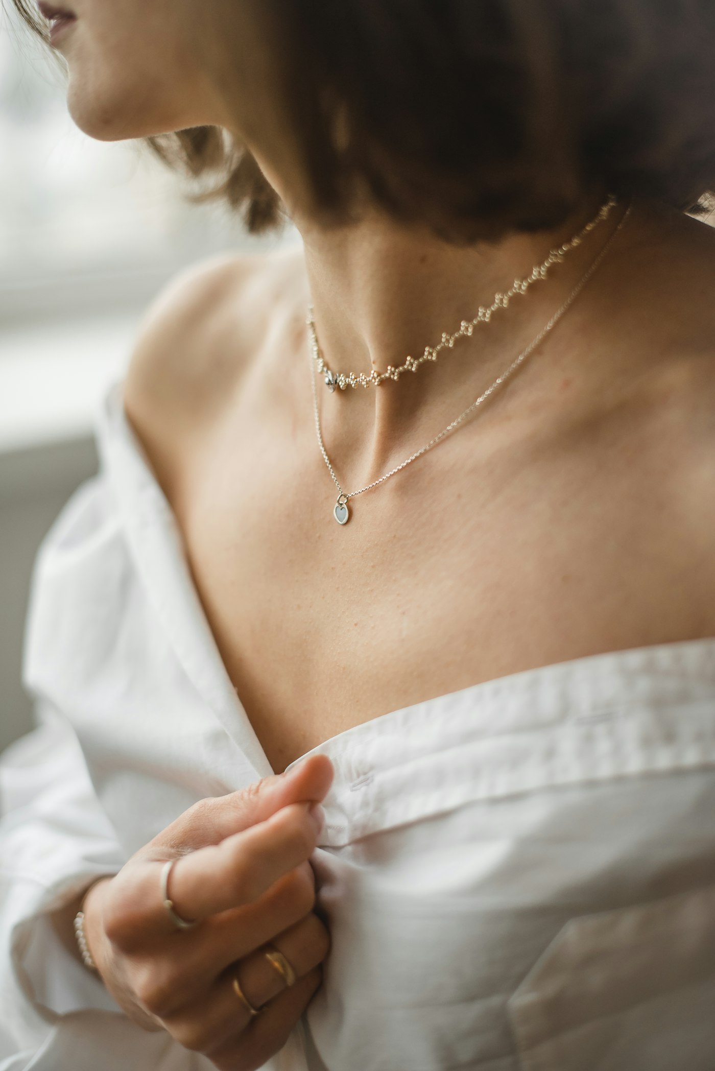 Layered necklaces worn close to the collarbone