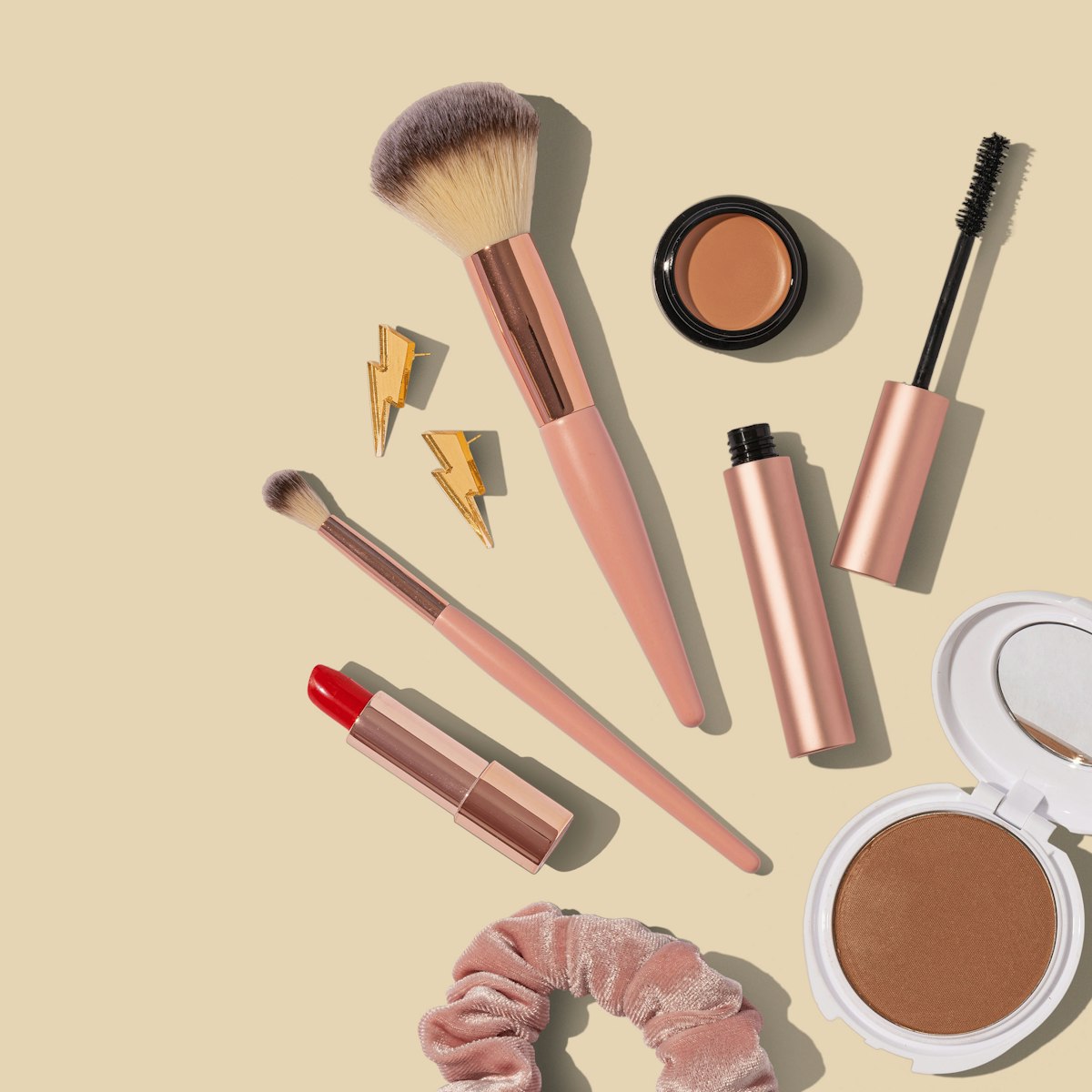 Lip color, brushes and compacts arranged on a warm background