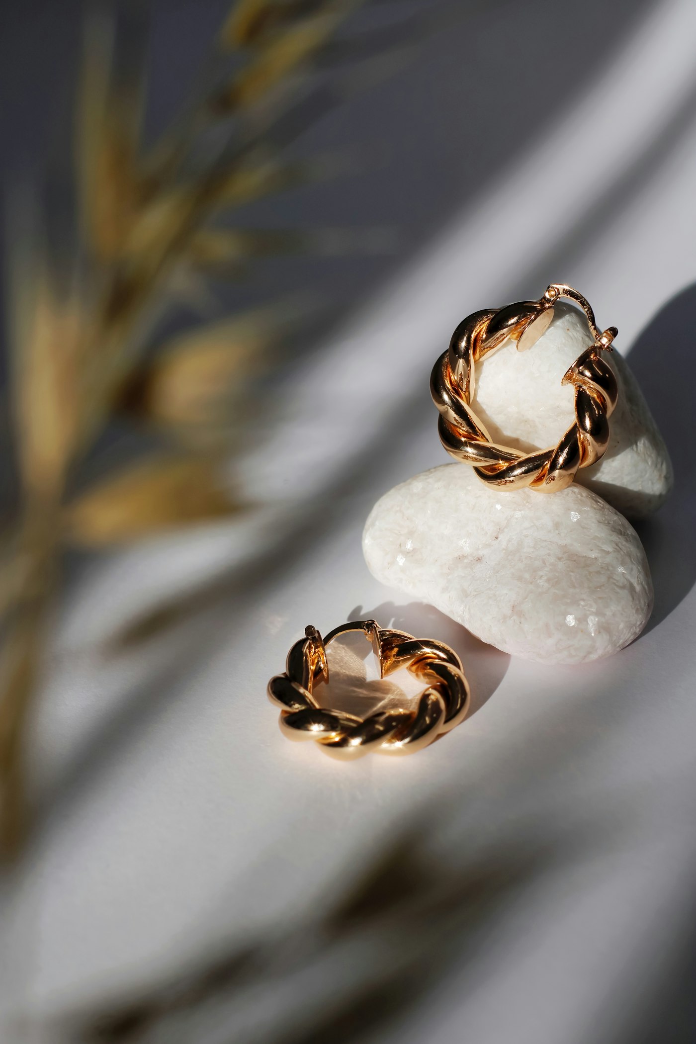 Twisted gold hoop earrings on pale stone