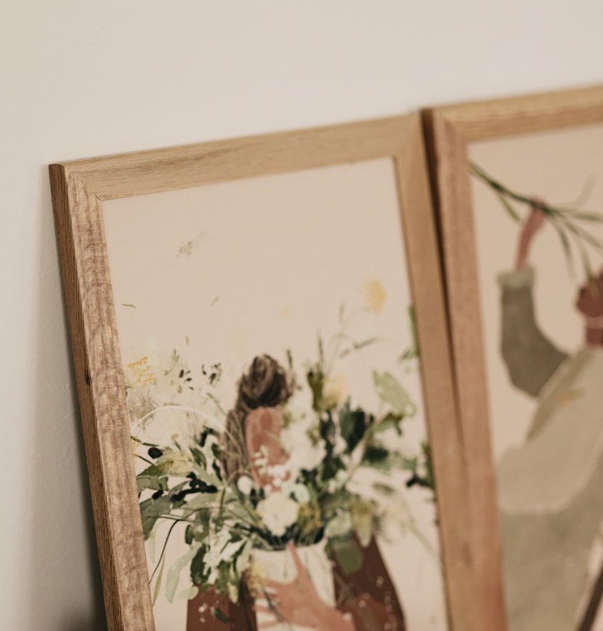 Two wood-framed floral illustrations leaning together
