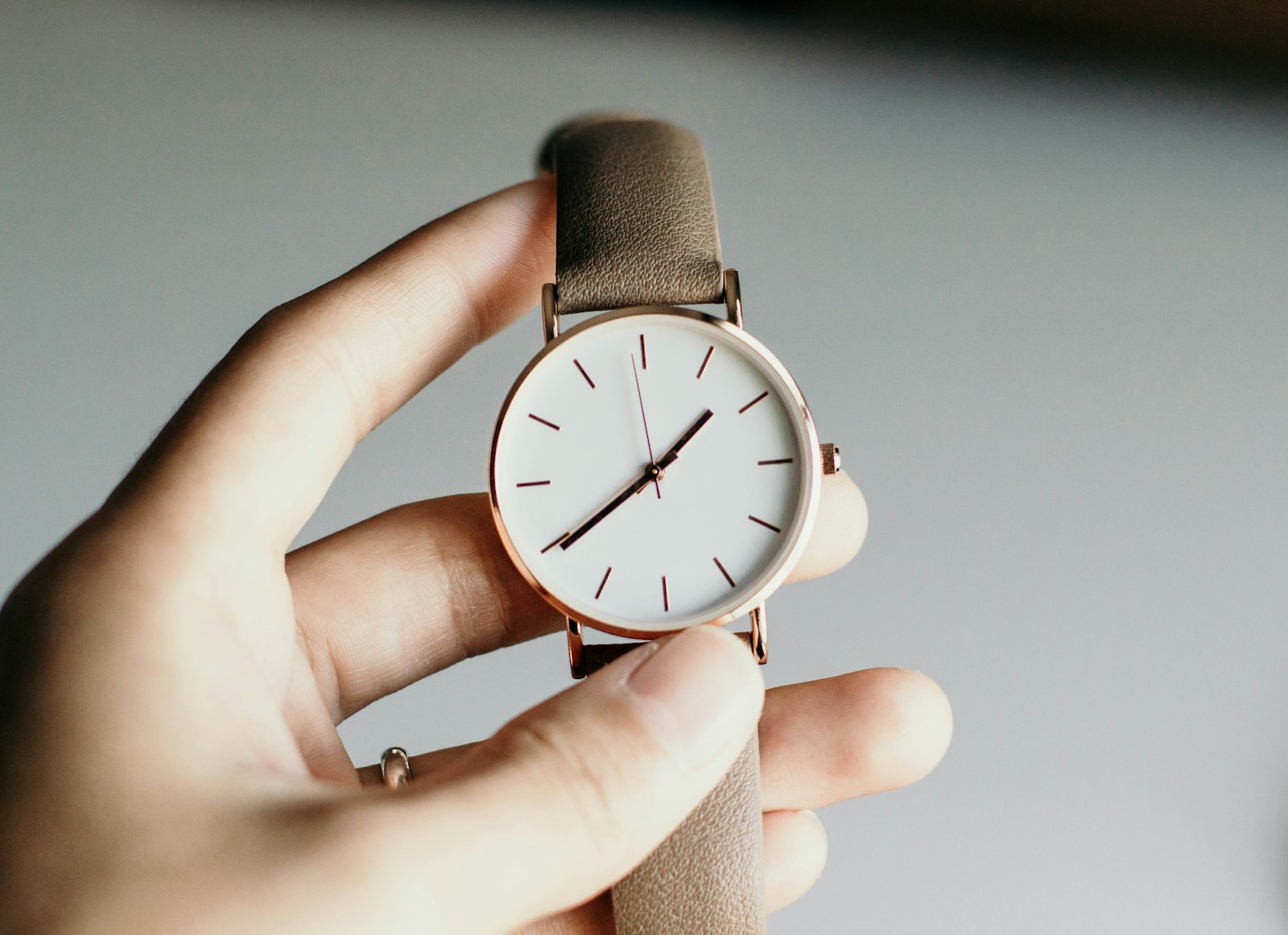 Minimal unbranded watch with a pale dial and taupe strap